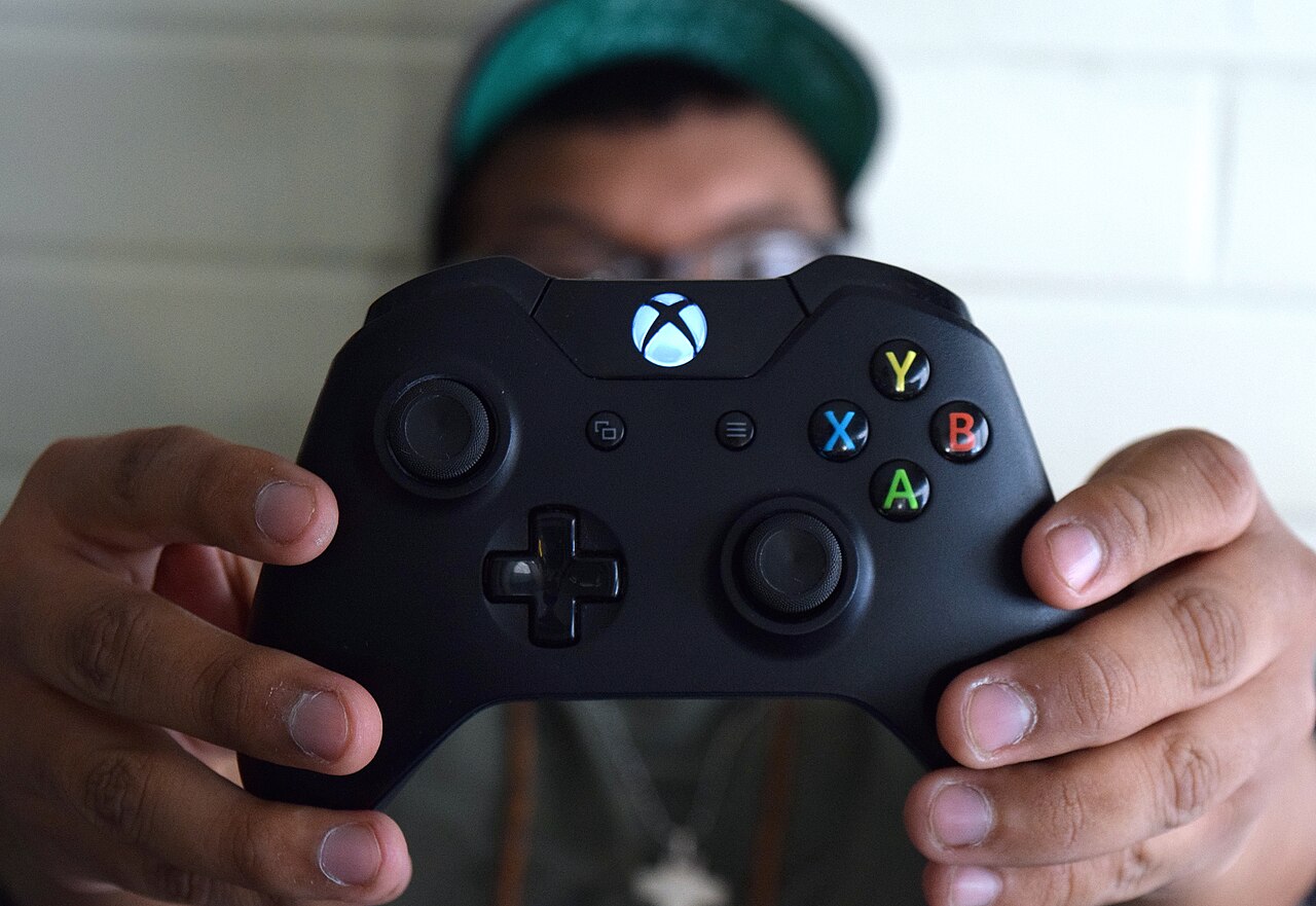 Hands holding a game controller with thumbs on the controls